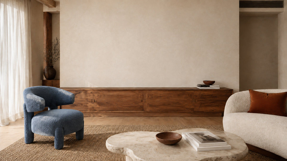 A sunlit living room with walnut furniture, a blue lounge chair and ivory sofa.